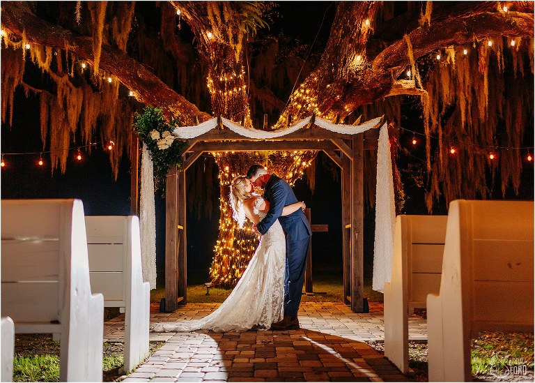 bride and groom share quiet moment under giant oak tree covered in twinkle lights at Ever After Farms wedding
