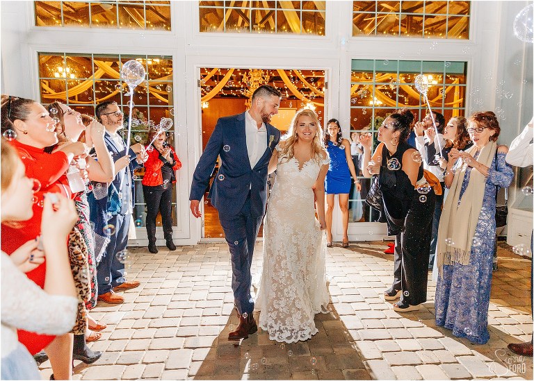 bride and groom laugh as they exit through bubbles at end of Ever After Farms wedding