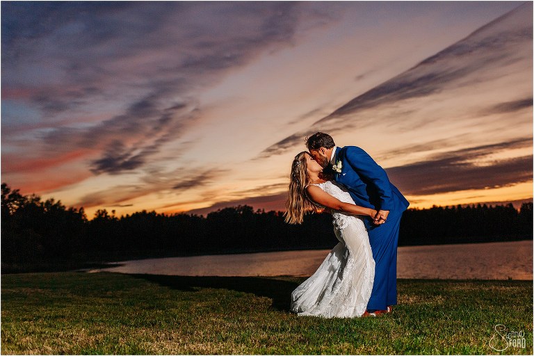 groom dips bride and kisses her as sun sets at Skyline Ranch wedding