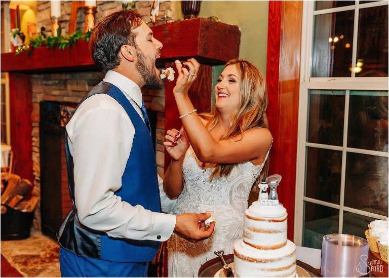 bride feeds groom cake with her hands at lakefront wedding reception