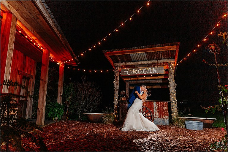 groom dips bride under the glow of the market lights at Isola Farms wedding