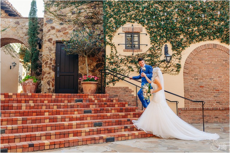 groom leads bride up brick staircase at Bella Collina wedding