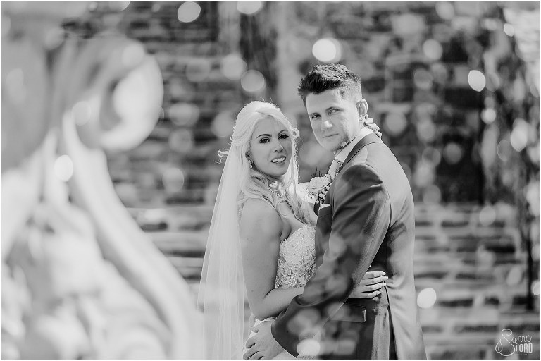 bride and groom look off through water in fountain at Bella Collina wedding