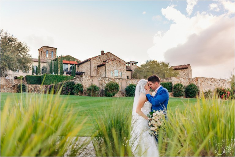 bride & groom kiss in front of clubhouse of Bella Collina wedding