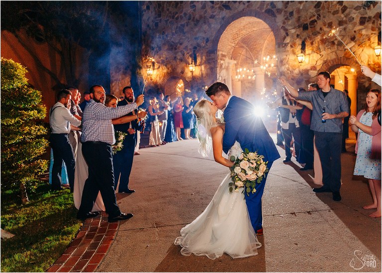 groom kisses bride as they make their grand exit from Bella Collina wedding under sparklers
