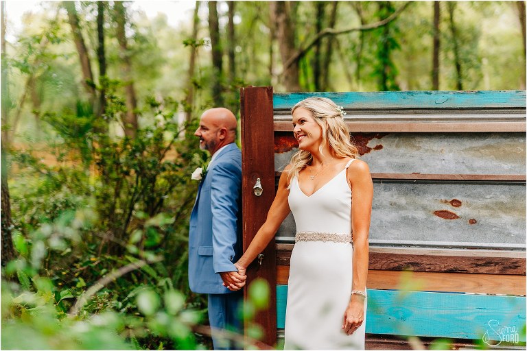 bride & groom hold hands during first touch before rustic barn wedding
