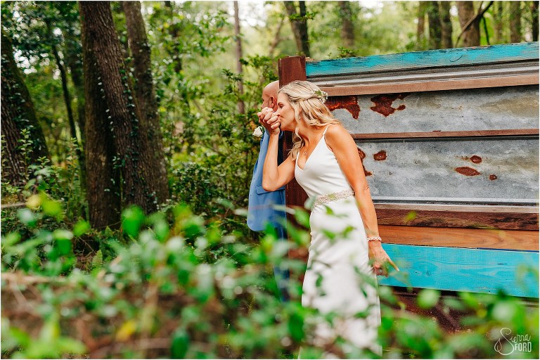 bride kisses groom's hand during first touch before rustic barn wedding
