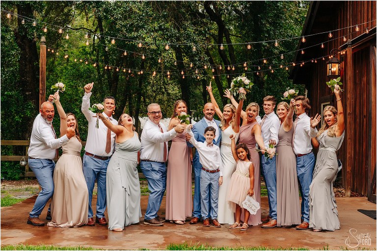 bride & groom laugh as wedding party cheers for them at rustic barn wedding