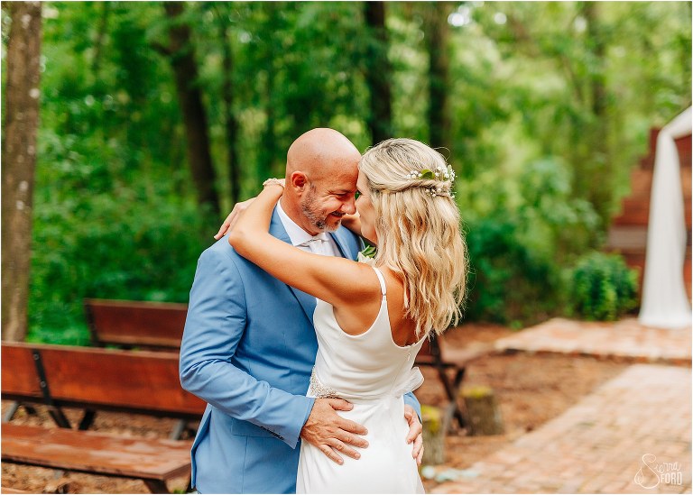 groom smiles as he meets foreheads with his new wife at rustic barn wedding