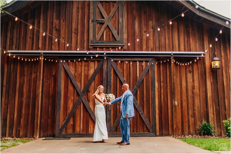 groom spins bride under market lights at rustic barn wedding