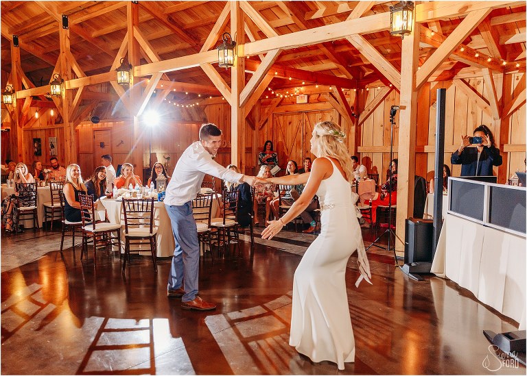 bride's son laughs as he spins his mother on the dance floor at rustic barn wedding