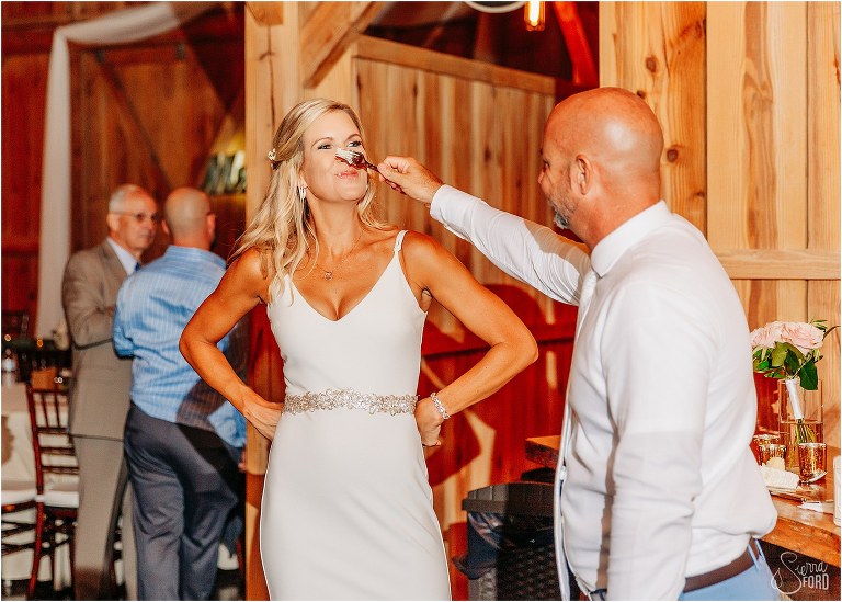 groom smashes cake on bride's nose at rustic barn wedding