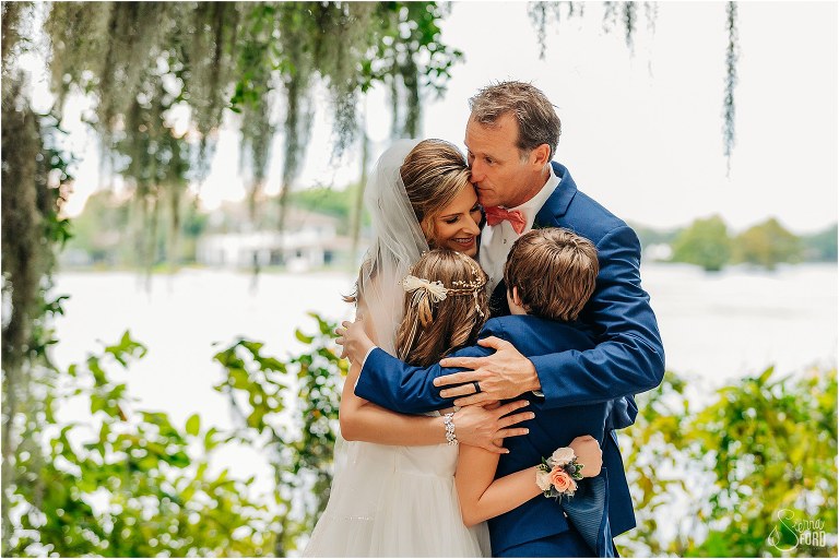 bride and groom share group hug with their children as their families become one atKraft Azalea park wedding