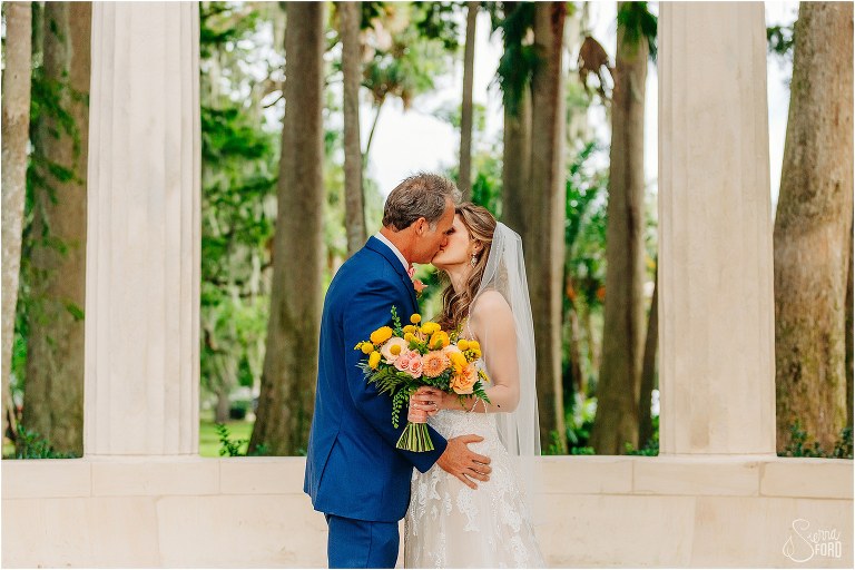 bride and groom share a kiss among the large stone columns at Kraft Azalea park wedding