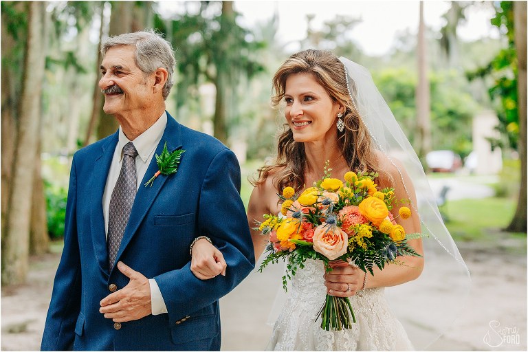 bride walks arm in arm with father carrying yellow and orange bridal bouquet at Kraft Azalea elopement