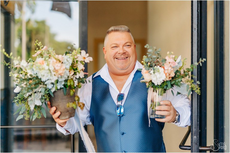 father of the bride beams as he carries the bouquets he's been tasked with to Tavares Pavilion wedding