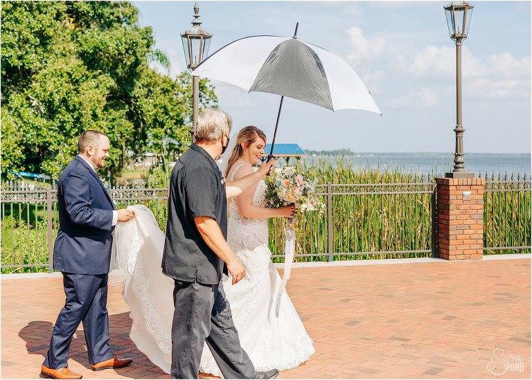 amazing Tavares Pavilion wedding staff covers bride with umbrella as they walk inside