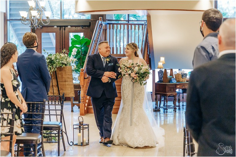 father of the bride squeezes daughter's hand as he walks her down aisle at Tavares Pavilion wedding