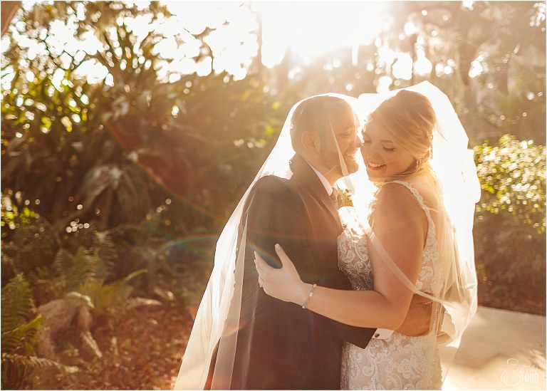groom nuzzles bride as they snuggle up under veil as sun sets at Tavares Pavilion wedding