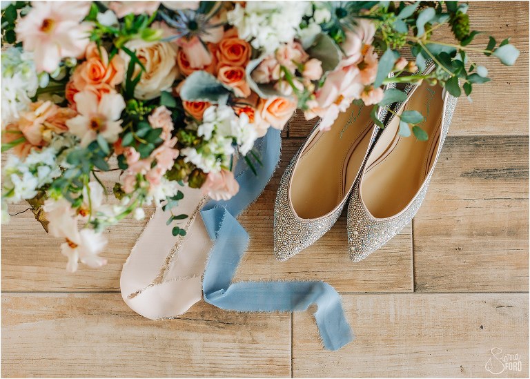 bride's sparkly blush shoes peek out from under peach and white bridal bouquet at Tavares Pavilion wedding