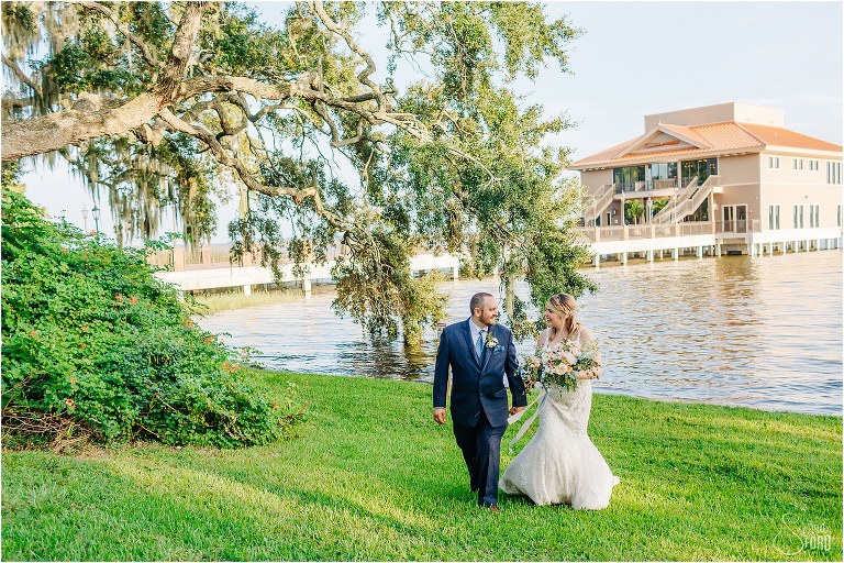 bride and groom walk together along lake at Tavares Pavilion wedding