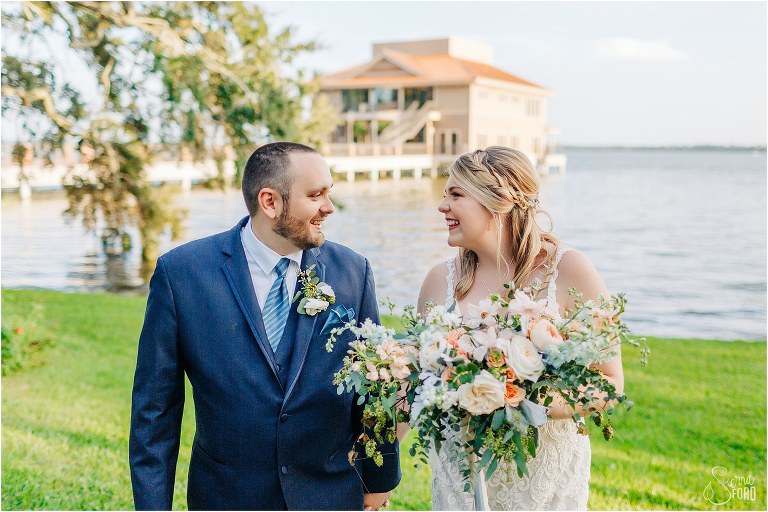 bride and groom laugh together as they walk by lake at Tavares Pavilion wedding