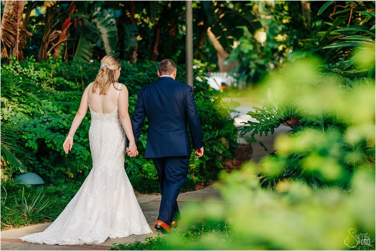 bride and groom walk hand in hand through Wooten Park to Tavares Pavilion wedding reception