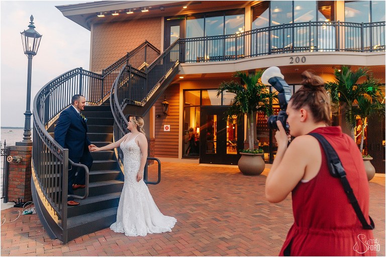 photographer directs couple on grand staircase at Tavares Pavilion wedding