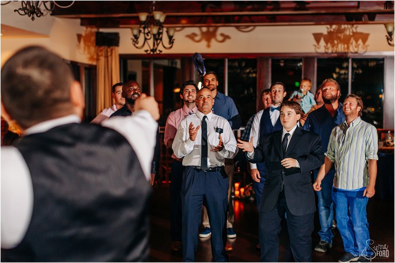 all the eligible bachelors reach for tossed garter at Tavares Pavilion wedding
