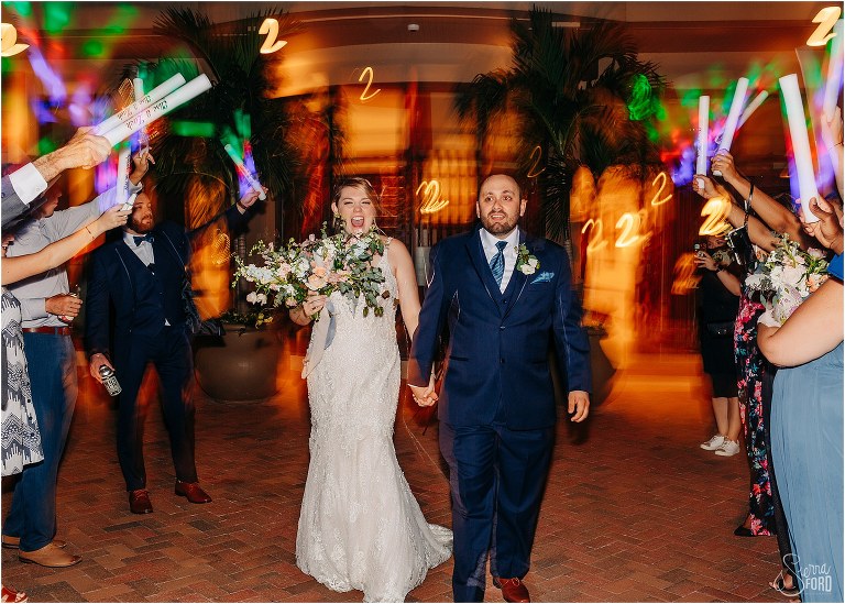 bride and groom laugh as rainbow glow sticks light up grand exit from Tavares Pavilion wedding