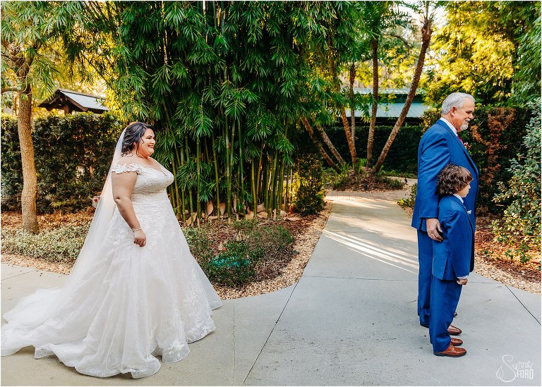 bride grins as she stands behind her father and son before their first look at rustic Apopka wedding