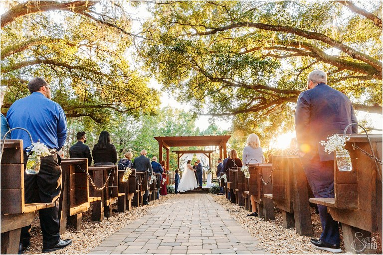 sun shines through live oaks as bride and groom exchange vows at Apopka wedding venue