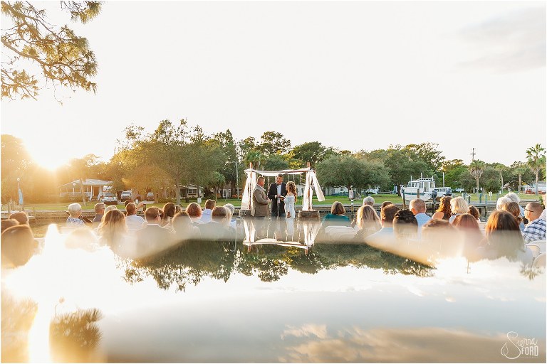 reflection of trees and sky as bride and groom exchange vows at St. Pete backyard wedding ceremony