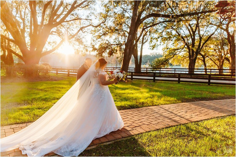 bride and groom walk arm in arm under the live oaks as the sun sets at Apopka wedding venue