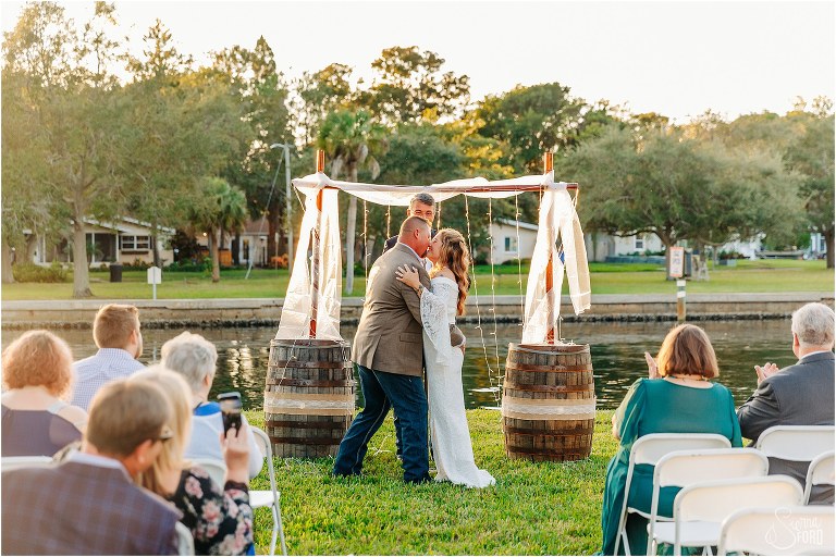 bride and groom laugh as they share first kiss as husband and wife at St. Pete backyard wedding ceremony