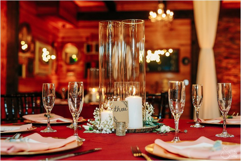 tall glass candle holder centerpieces on maroon linen at rustic Apopka wedding