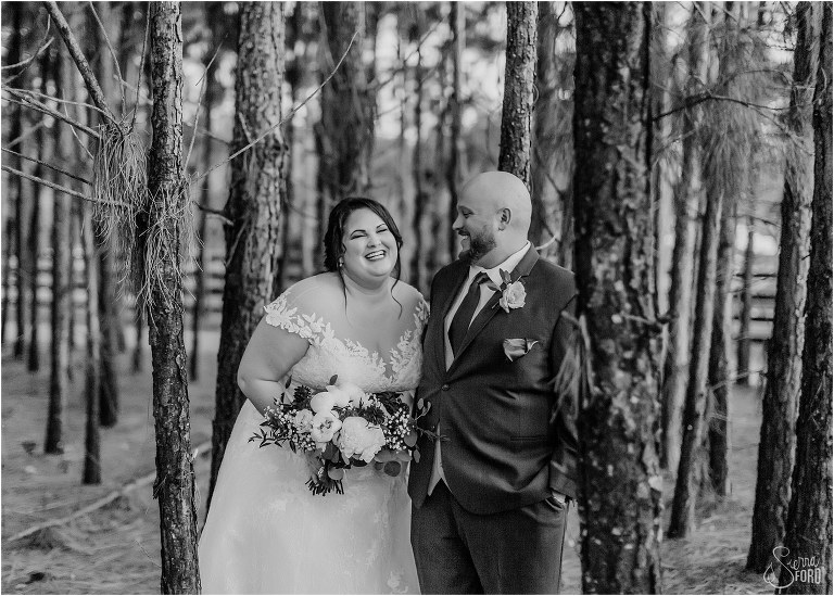 bride and groom laugh as they stand amongst the trees at rustic Apopka wedding