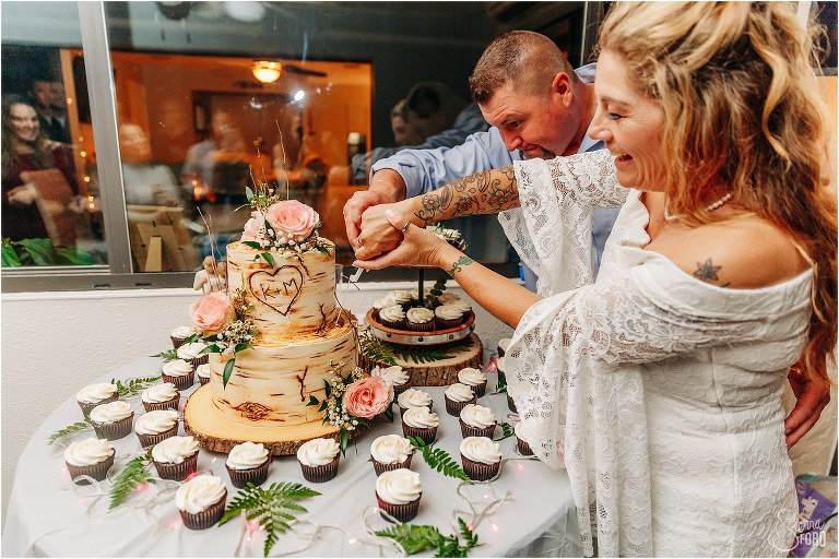 bride and groom laugh as they try to cut cake at St. Pete backyard wedding reception