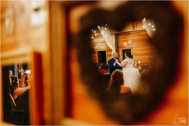 reflection of bride and grooms sharing first dance in heart-shaped mirror