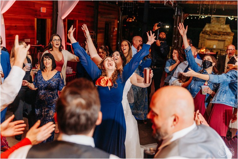 bride throws her hands in the air on the dance floor with her girls