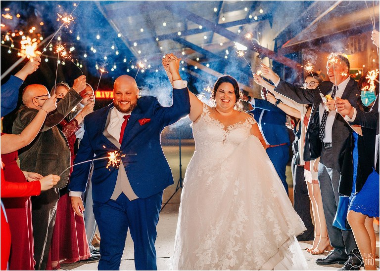 bride and groom laugh as they exit rustic Apopka wedding through sparkler tunnel