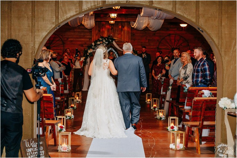 guests look on lovingly as father escorts bride down aisle at Hidden Barn wedding