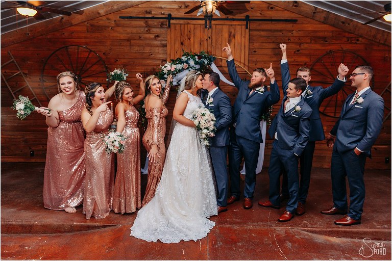 bride & groom kiss while wedding party cheers at Hidden Barn wedding