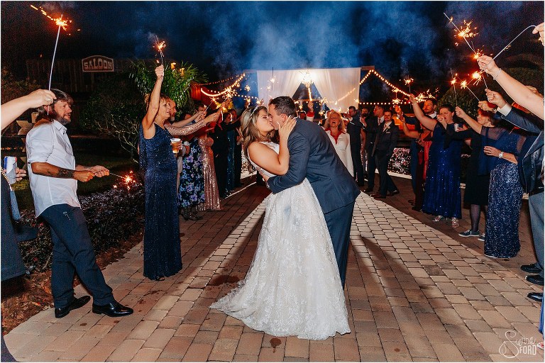 groom dips bride with a kiss as they go through sparkler tunnel exit at Hidden Barn wedding