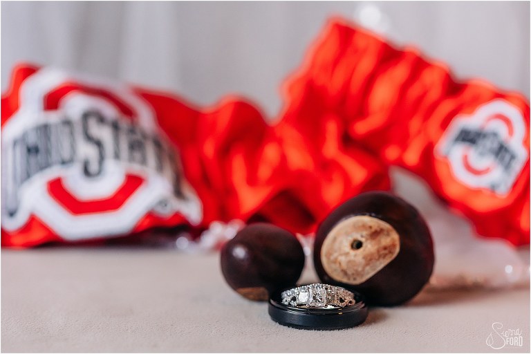 couple's wedding bands sit in front of Ohio State garters before The Acre Orlando wedding
