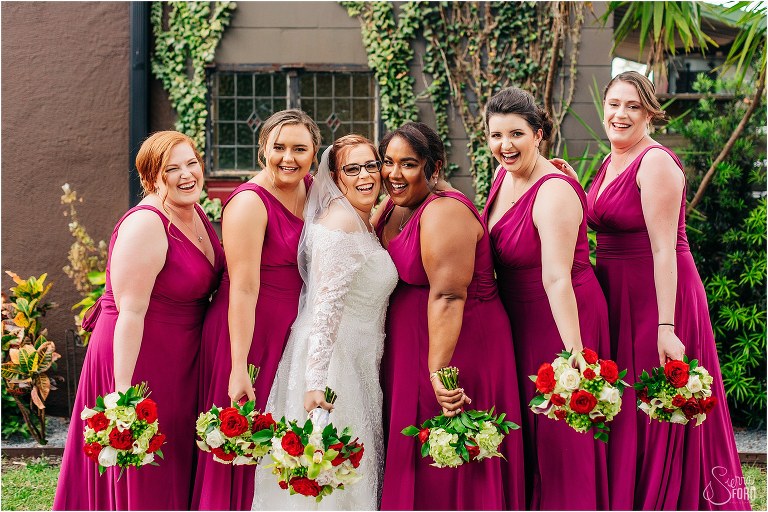 bride laughs with her bridesmaids in fuchsia dresses at The Acre Orlando wedding