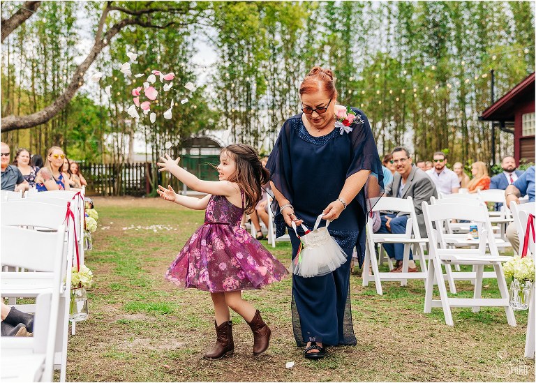 flower girl twirls as mother of bride holds basket of petals at The Acre Orlando wedding ceremony