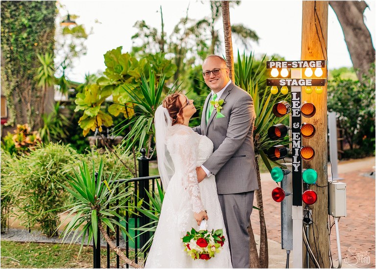 bride & groom beam next to custom race light stand at the acre orlando wedding