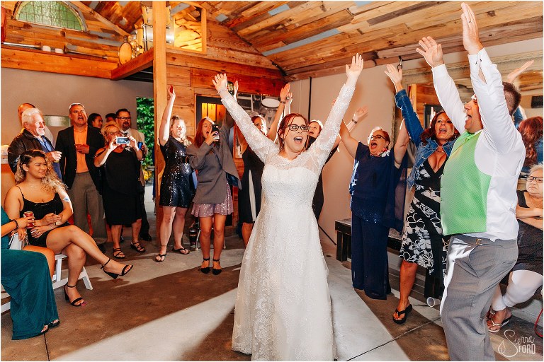 bride throws her hands up on the dance floor with her loved ones at The Acre Orlando wedding