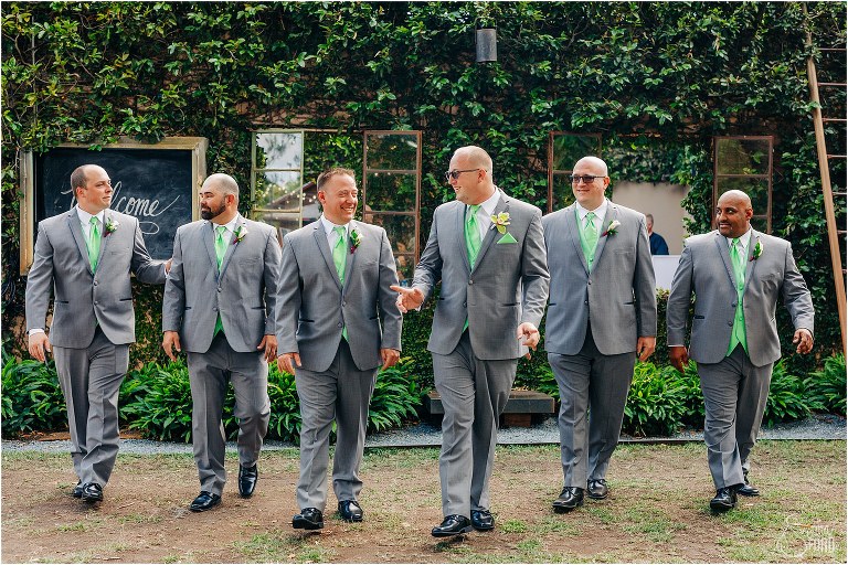 groom and groomsmen stroll in slate grey suits with mint green accessories at The Acre Orlando wedding